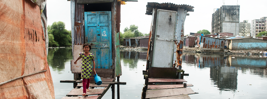 Eriam Sheikh,7 year old comes out after using the toilet on stilts or floating toilet built over a drain passing by Rafiq Nagar in Mumbai. PHOTO:UN Water